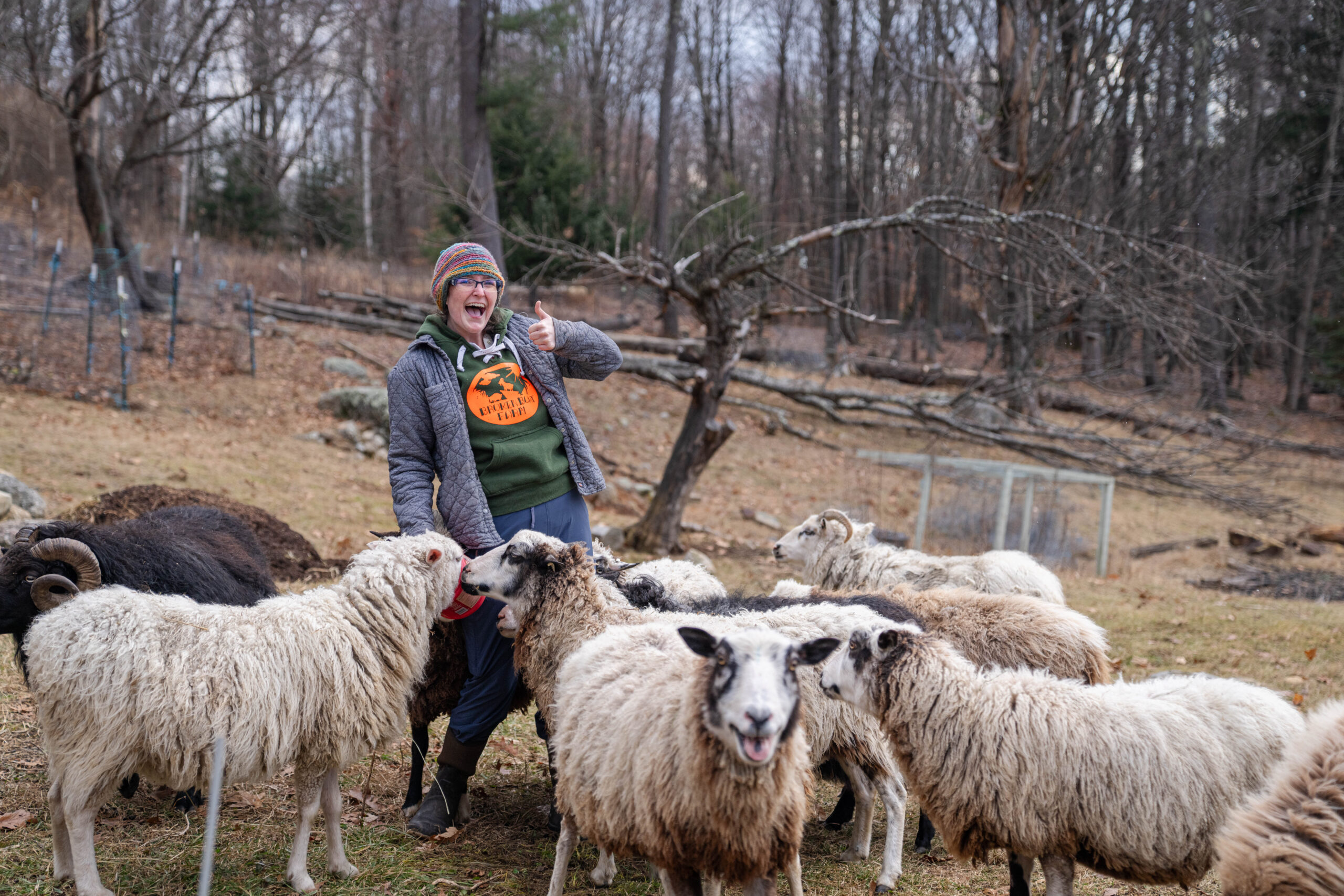 Farming business owner, Kelly McCutcheon, surrounded by white and brown sheep.