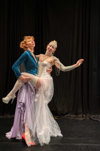 Two women in burlesque costumes dancing together. 