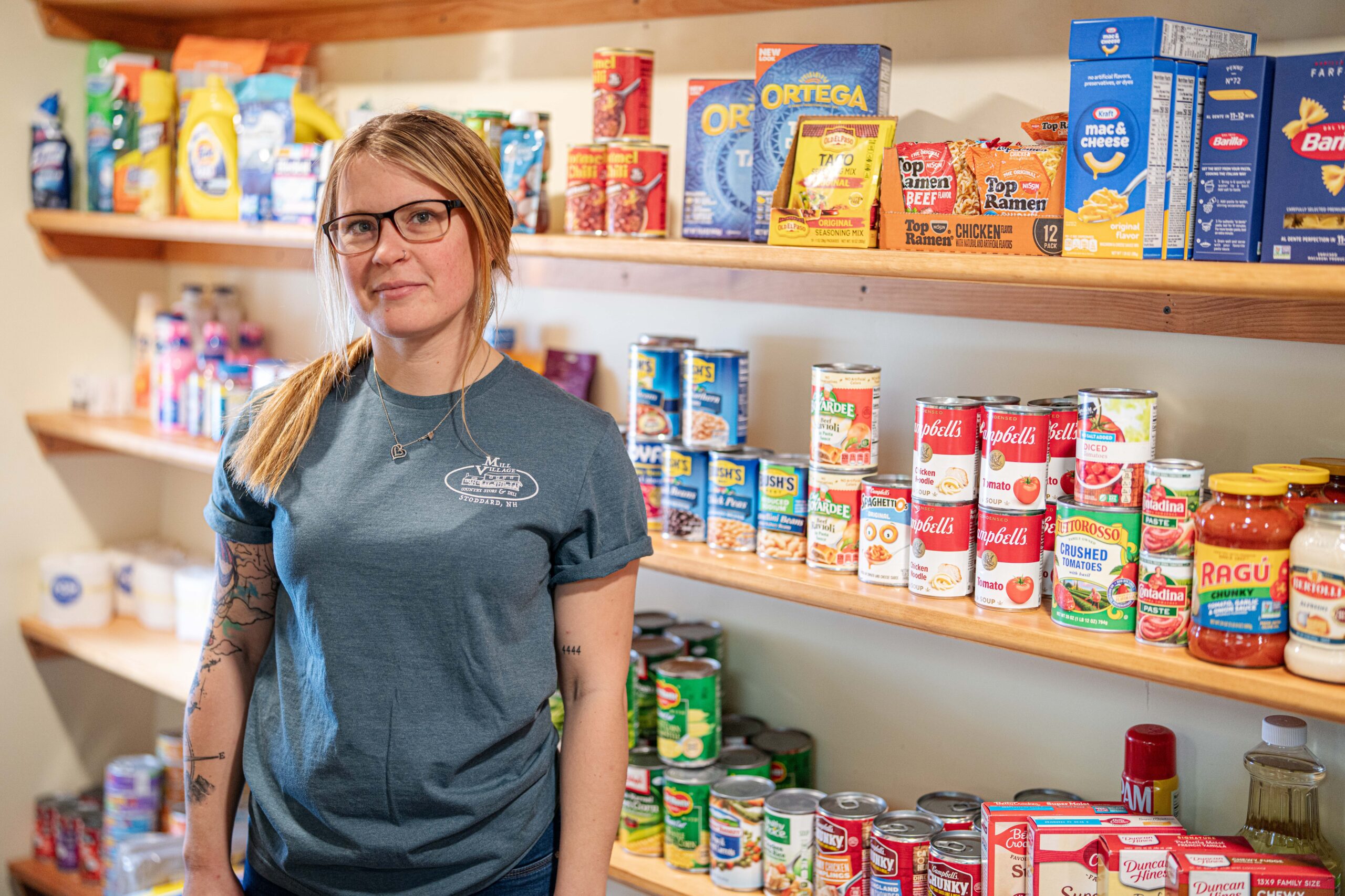 Small business owner standing in front of store shelves with non-perishable groceries.