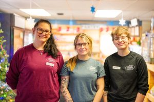 Three women smiling in Mill village t-shirts.