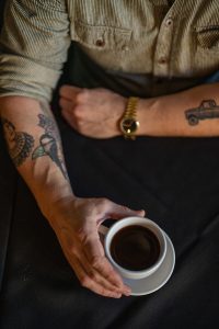 A cup of coffee in a white cup and saucer held by Owen.
