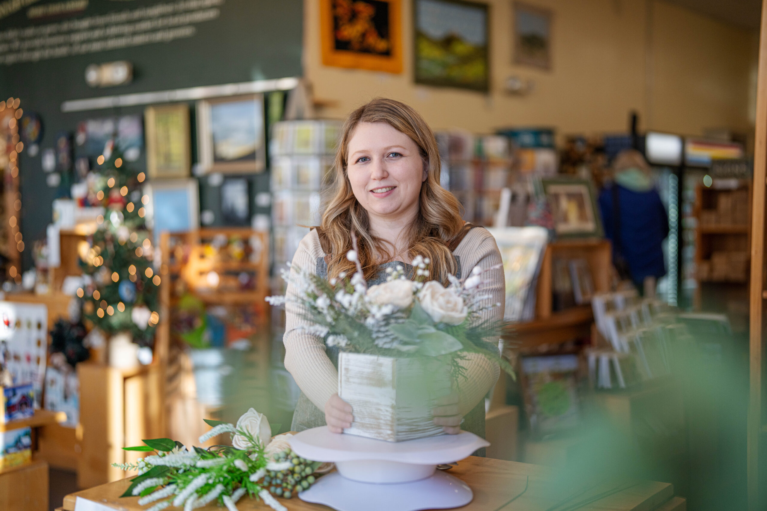 A white, blond woman arranging flowers in a store.