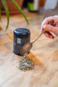 A spoon dropping tea leaves into a pile