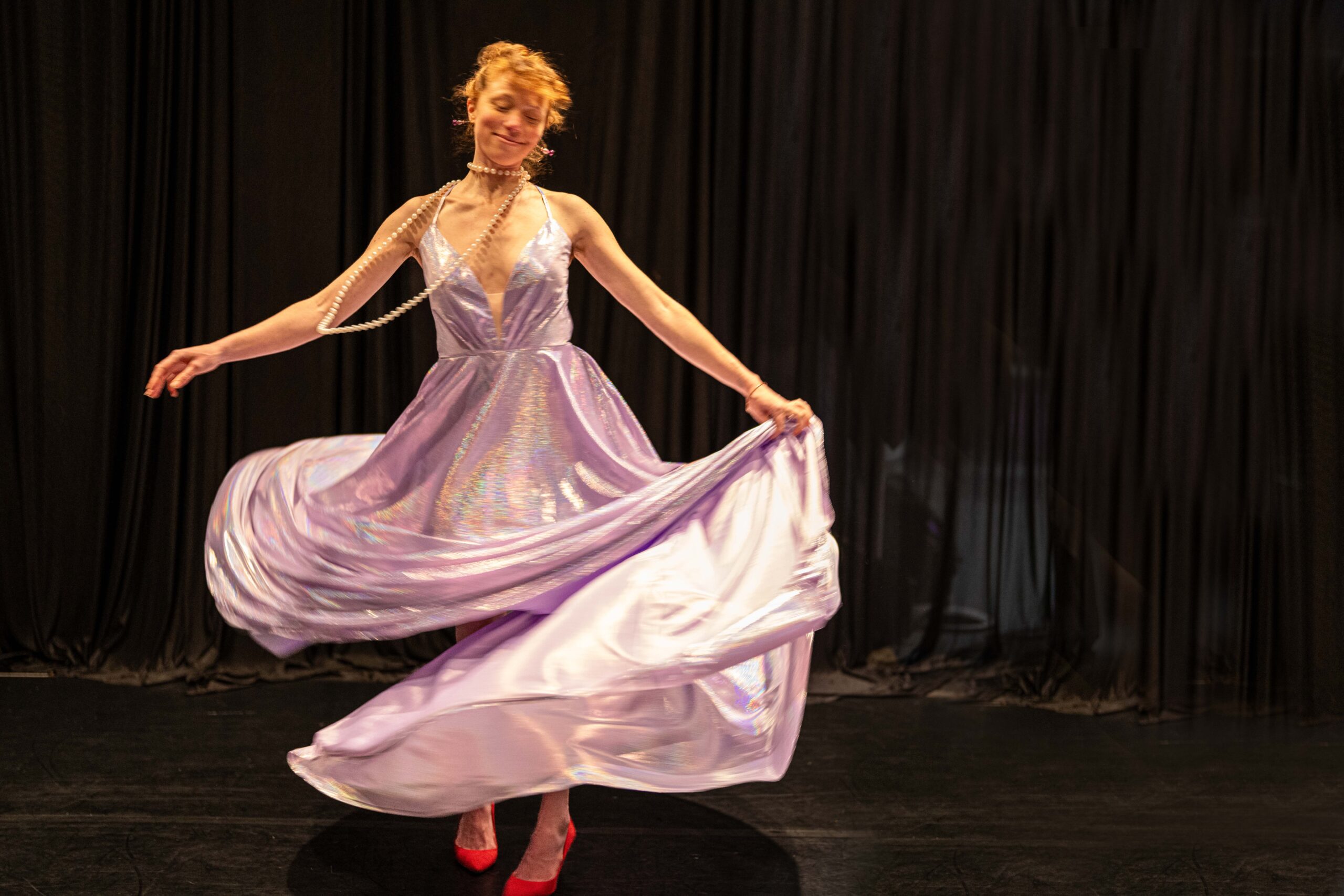 A white woman with red hair spinning in a purple dress.