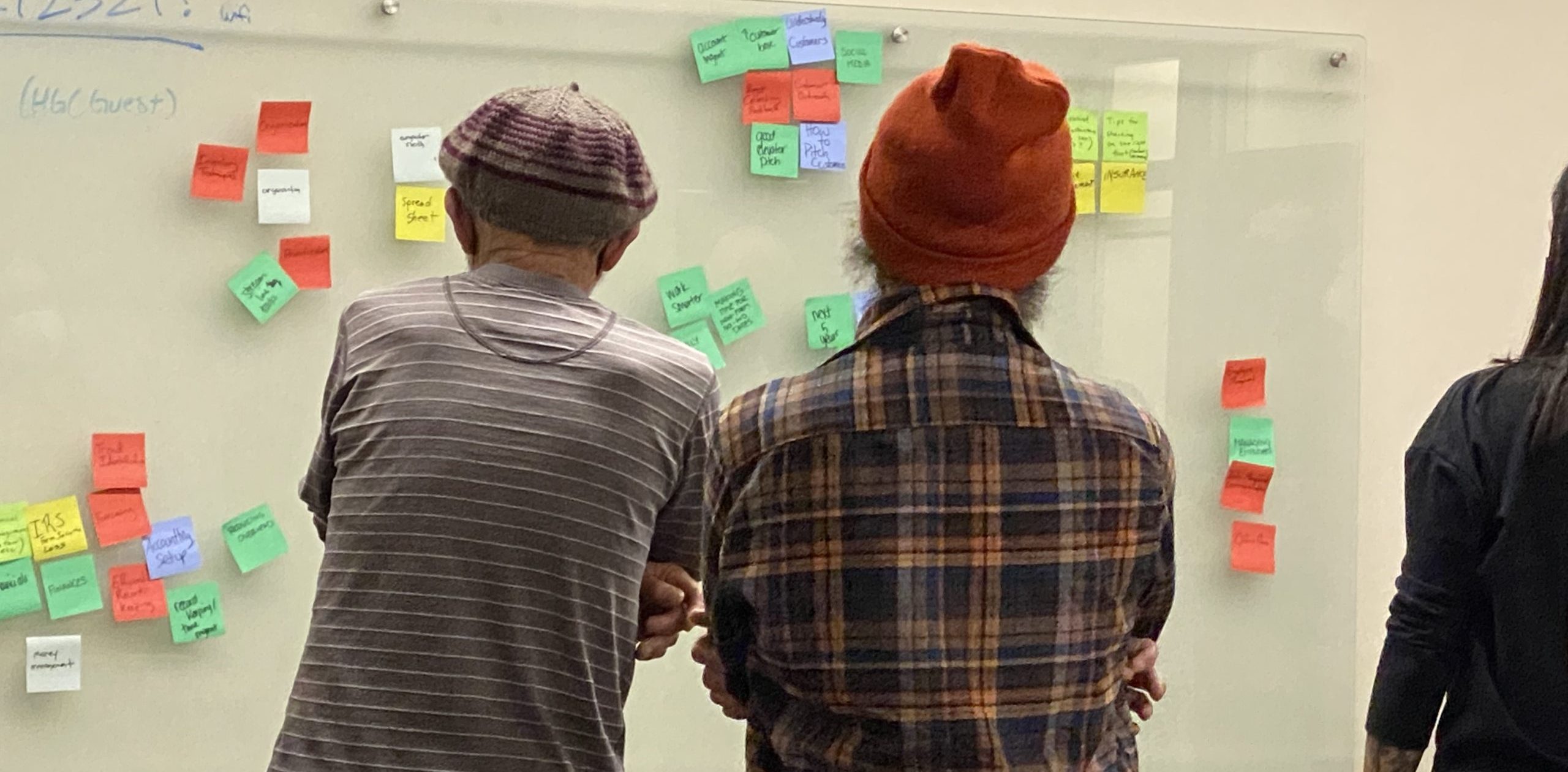 Two people looking at a wall with sticky notes